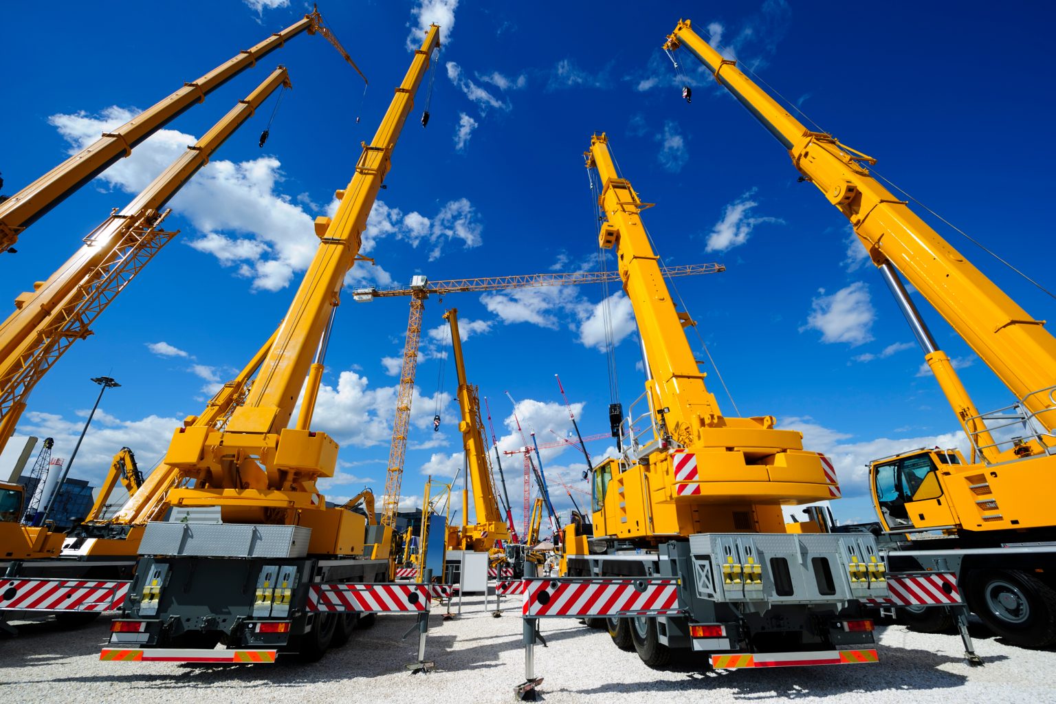 Yellow mobile cranes at a construction equipment yard